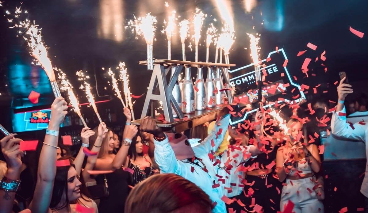 Crowd celebrating with raised sparklers inside a nightclub in Valencia.