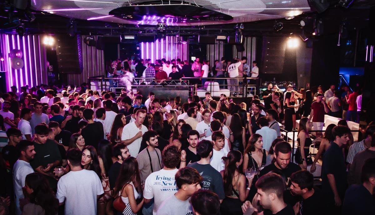 Packed main room of a nightclub with stage lighting in Valencia.