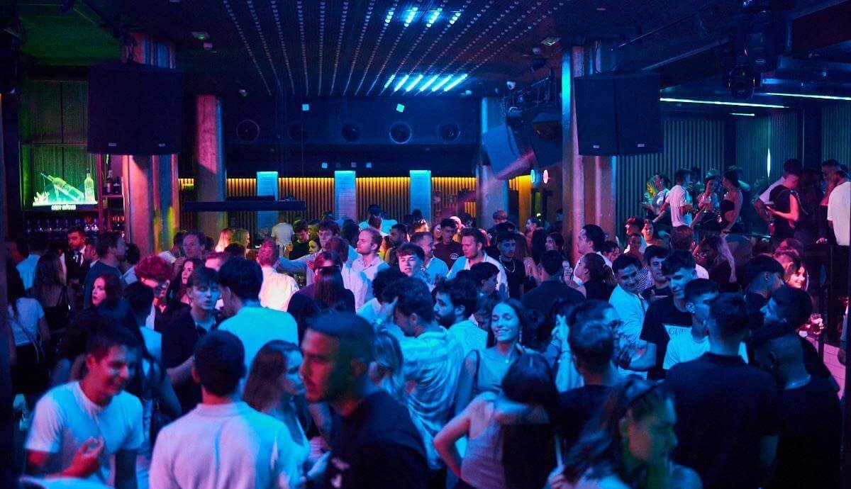 Packed dancefloor in a nightclub with blue lighting in Valencia.