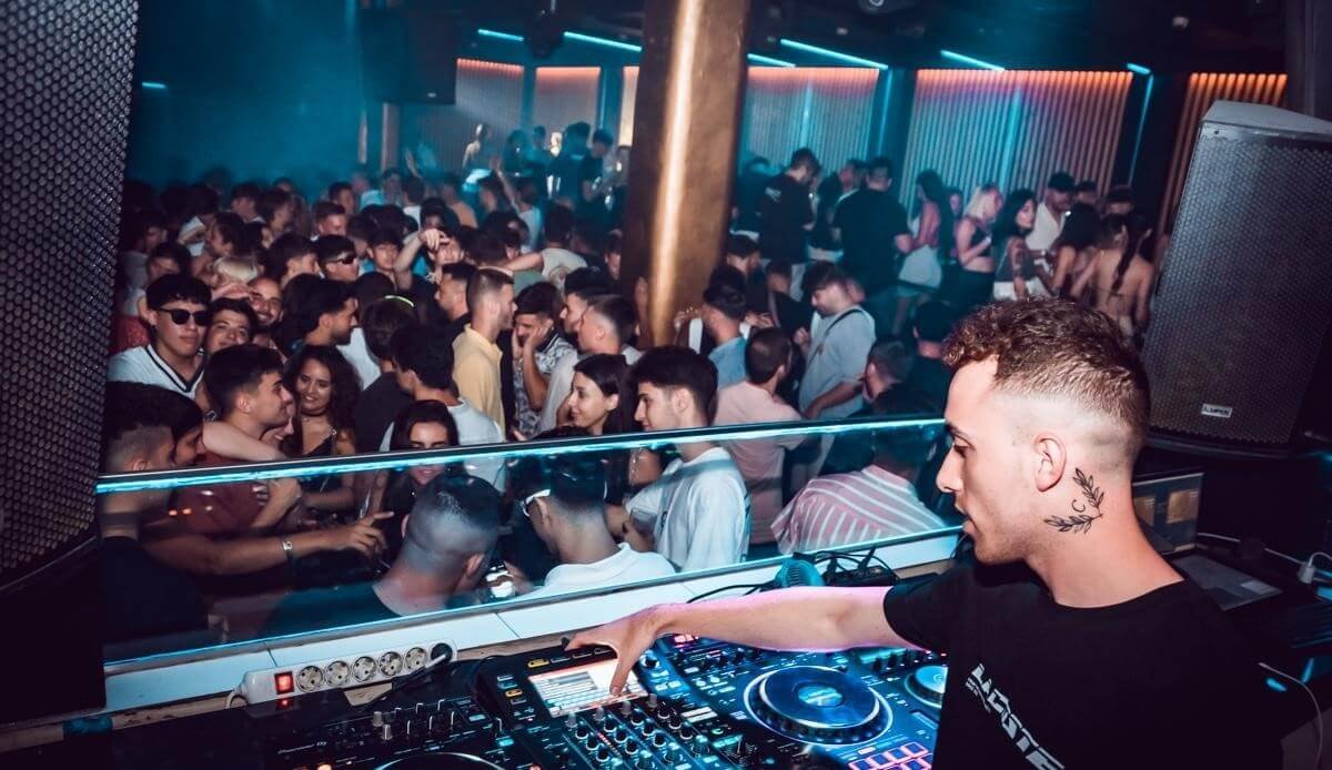 DJ performing to a crowded dancefloor in a Valencia club.