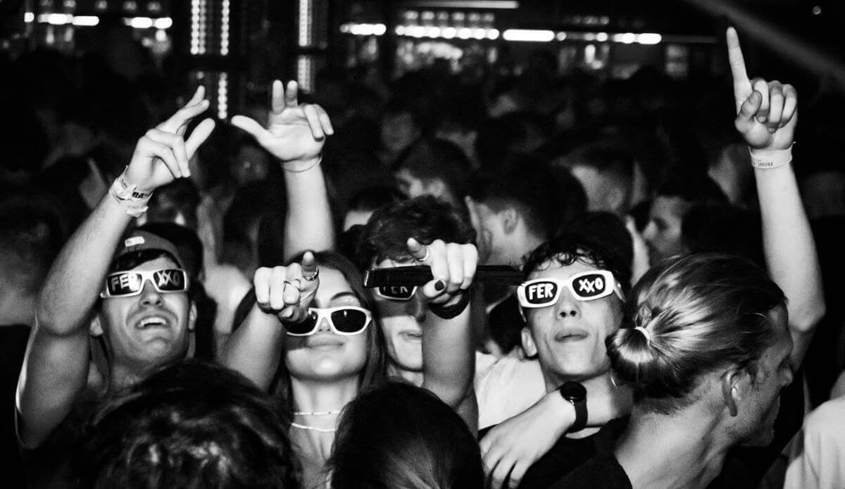 Friends dancing and cheering in a crowded club, black-and-white photo.