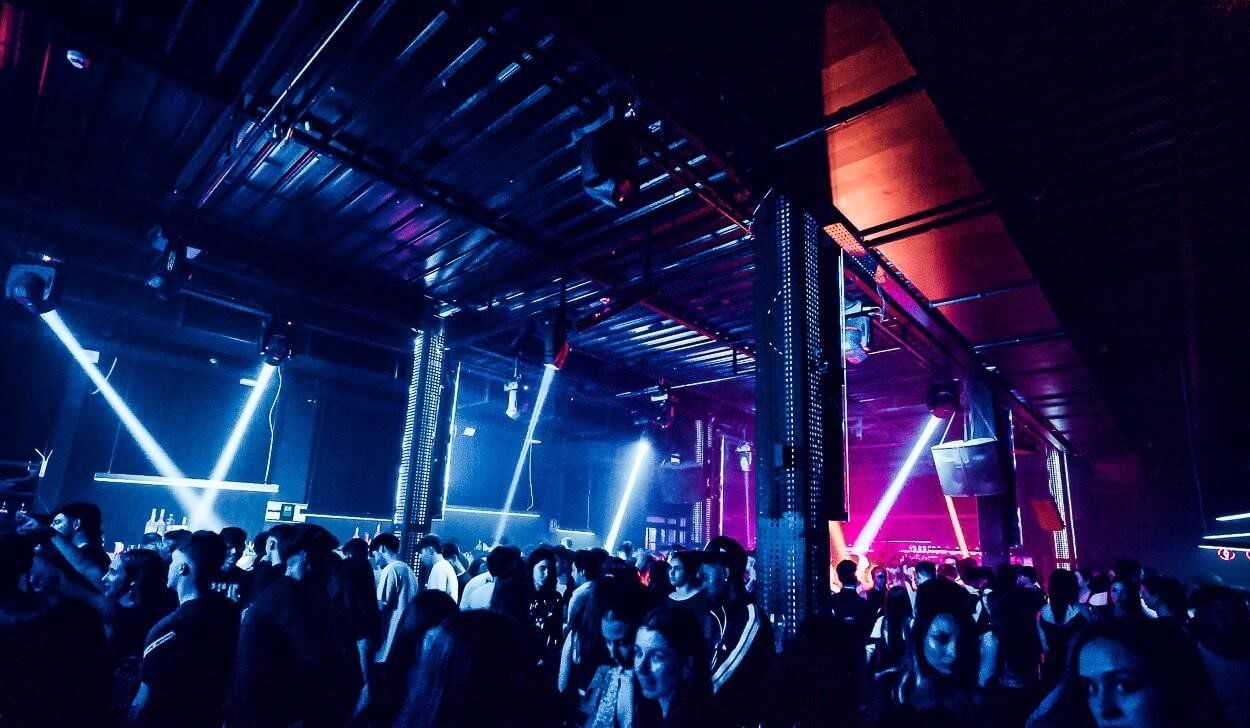 Nightclub crowd under blue and purple lights inside a beach club venue.