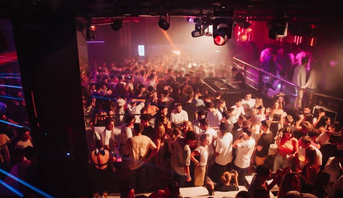 Large dancefloor crowd in a nightclub with warm lighting in Valencia.