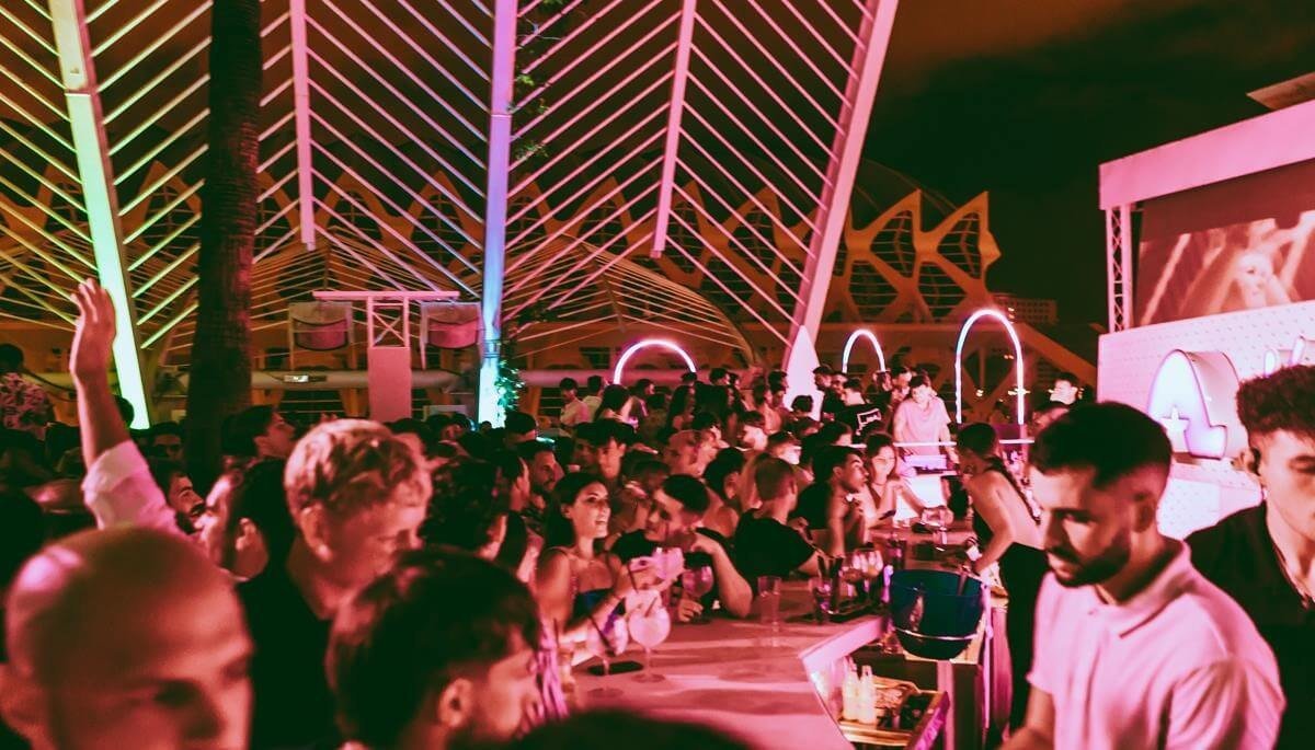 Open-air terrace crowd under pink and purple lights at night in Valencia.